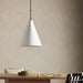 Conical pendant light Grazia matte white plaster with antiqued iron hardware hanging above a wooden table with minimal decor against a beige wall