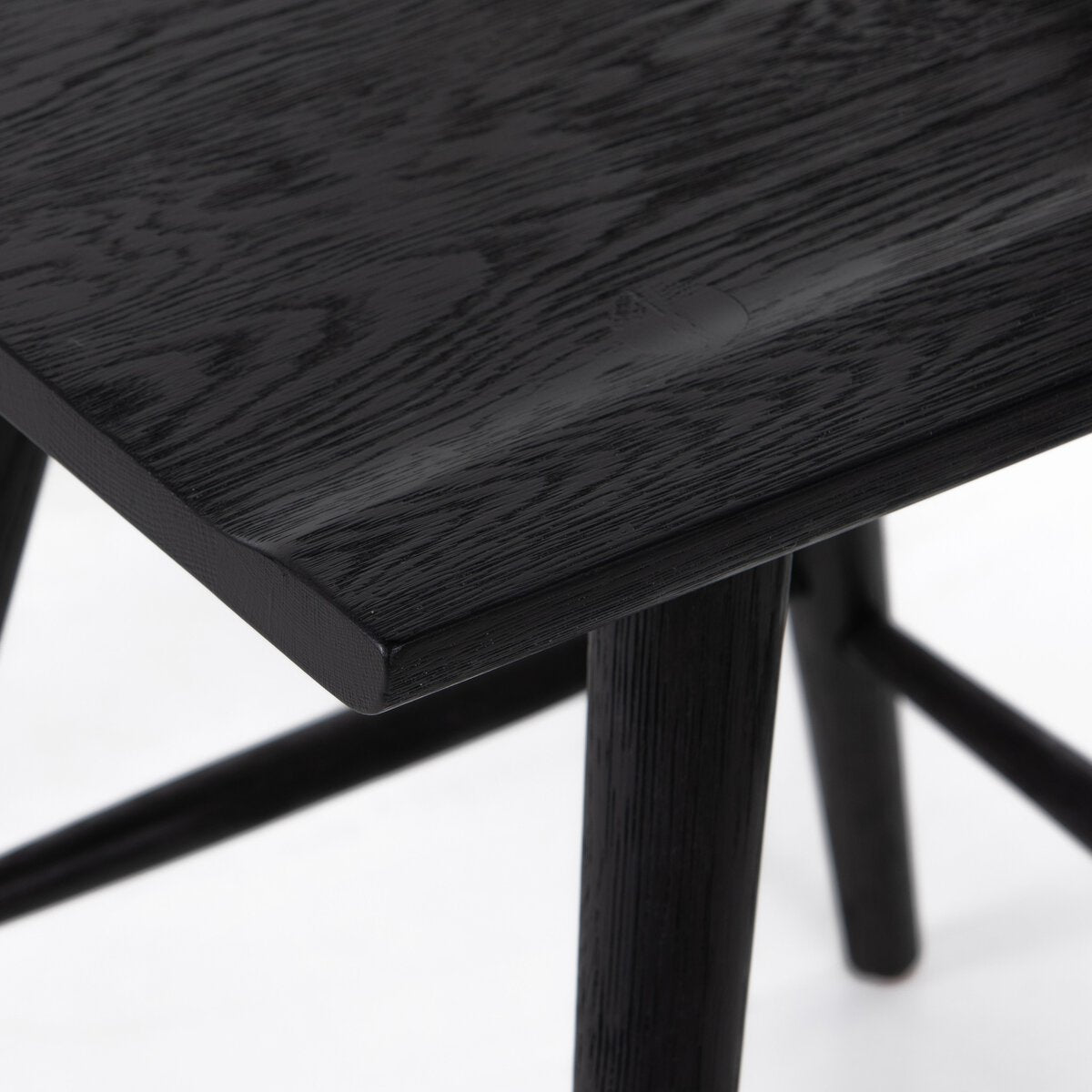 Black oak counter stool seat corner detail with dark woodgrain tabletop and legs