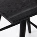 Black oak counter stool seat corner detail with dark woodgrain tabletop and legs