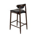 Bar stool with black upholstered seat and curved back, dark wood legs and footrest