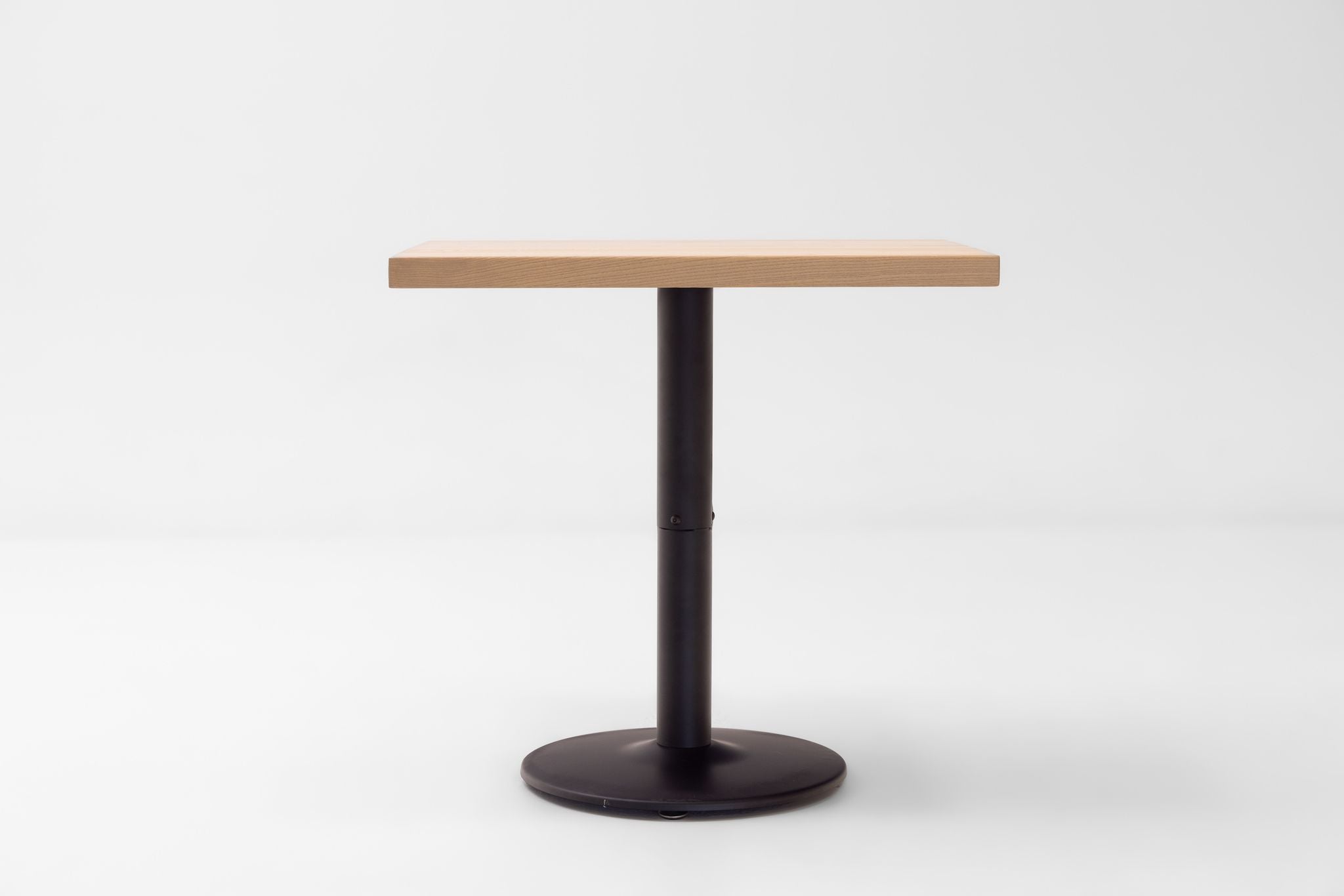 Rectangular ash table top on black round pedestal base, smooth natural wood grain