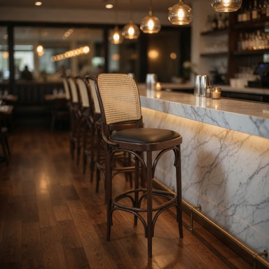 Theo bar stool in bar setting, beige woven back with dark round seat and wood frame