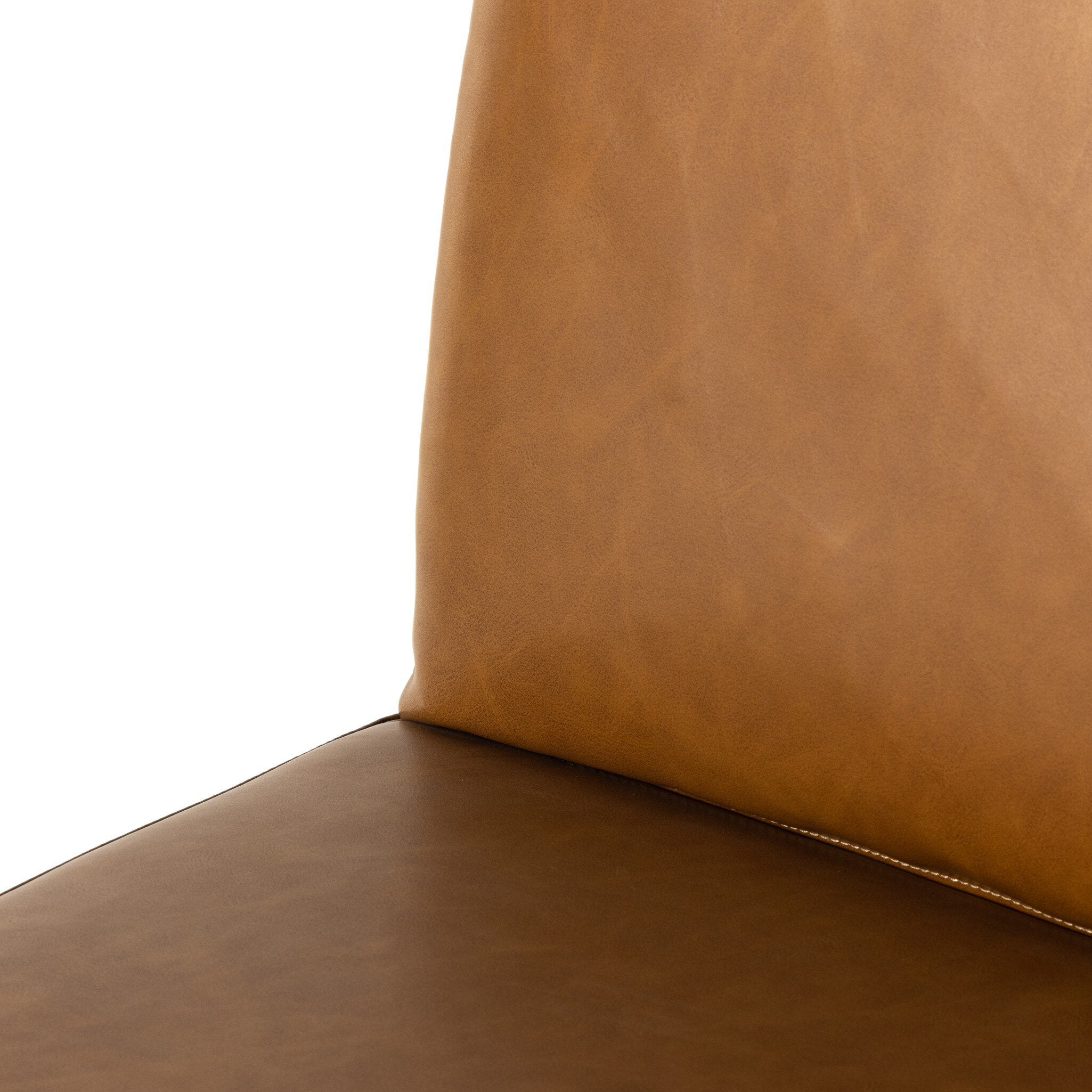 Close-up of tan leather-look counter stool seat corner with stitched edge