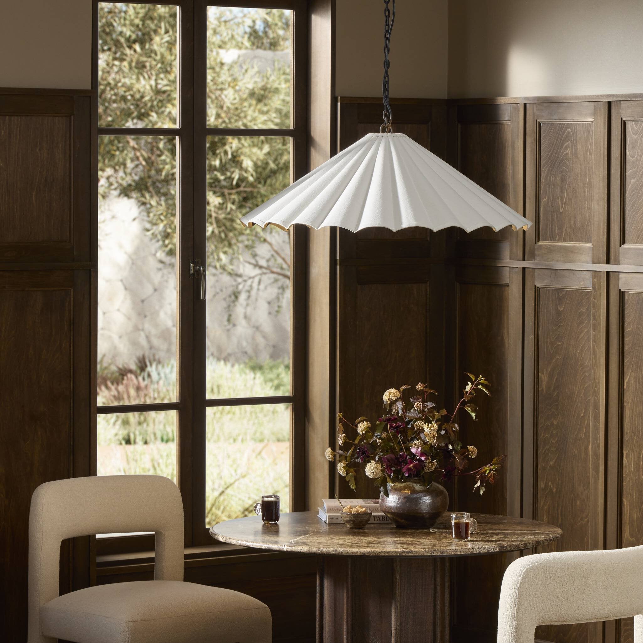 Fiorella 34-inch scalloped cream canvas pendant light with antiqued brass interior over wooden dining table area for hospitality inspiration