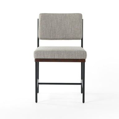 Gray upholstered chair with wooden legs on a white background. Benton Dining Chair in Savile Flannel performance fabric featuring a slim iron frame and wood bar.