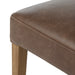 Brown upholstered chair seat edge with rounded seam and light wood leg.