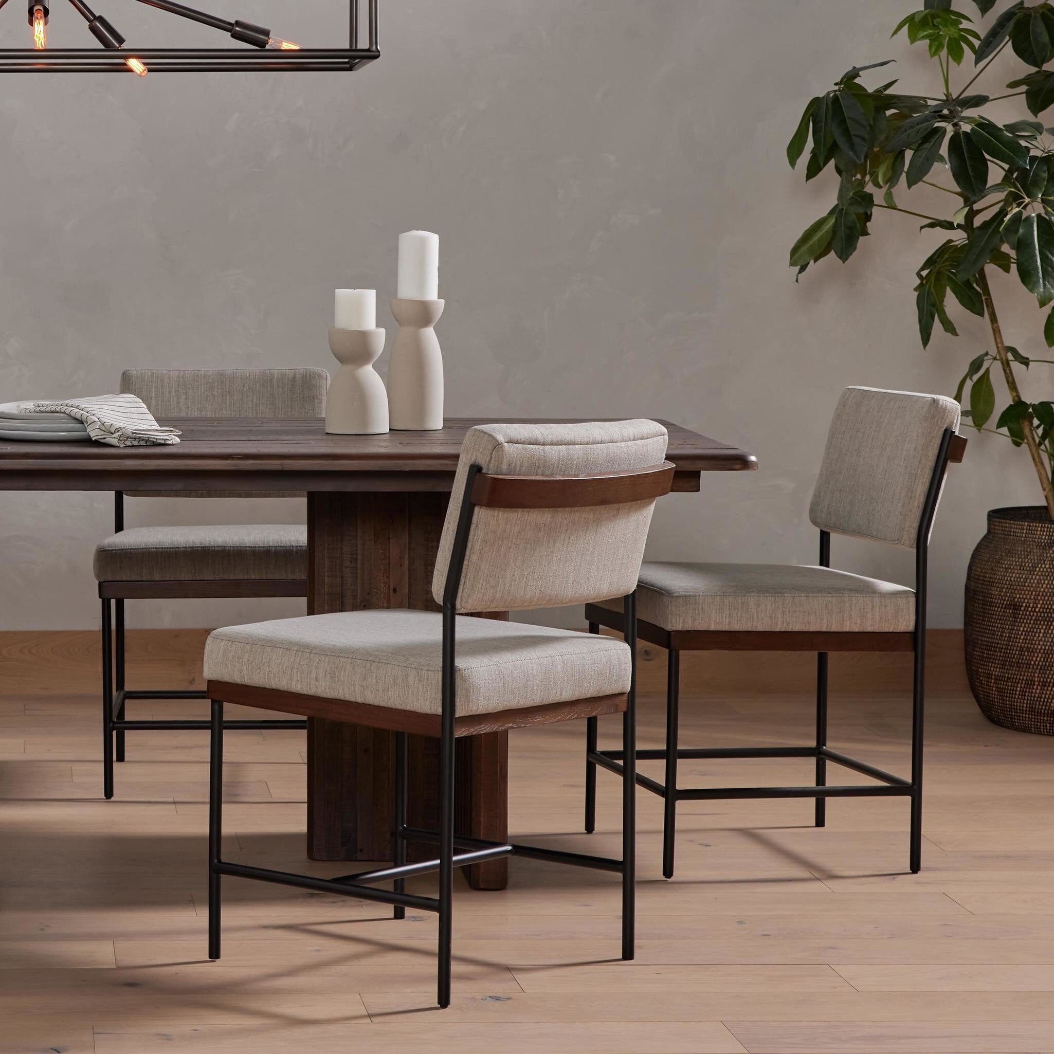 Dining room with wooden table and chairs, decorative vases, and a plant. Hospitality scene Benton Dining Chair in Savile Flannel performance fabric featuring a slim iron frame and wood bar.