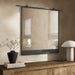 Chico square wall mirror featuring a unique vertical suspension bar in a hand-applied antiqued iron finish with black frame on a beige wall above a wooden console table with decorative items