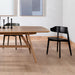Black armless dining chair with curved backrest and round seat, tapered legs