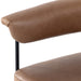 Close-up of tan cushioned stool armrest and edge, with black metal support