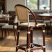 Bar stool with warm wood frame and beige speckled woven back and seat, close-up