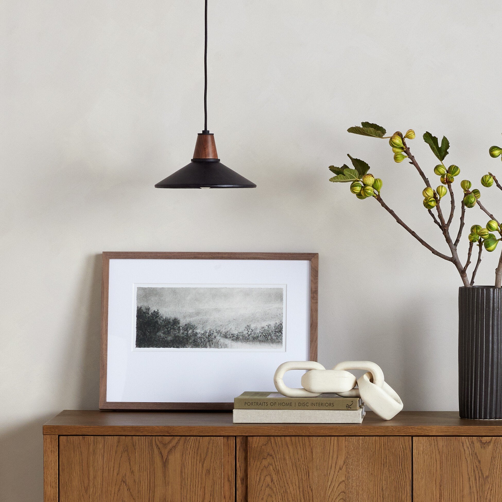 Modern interior with wooden sideboard, framed picture, decorative vase, and Cullen pendant light with a black leather shade and natural walnut finial 