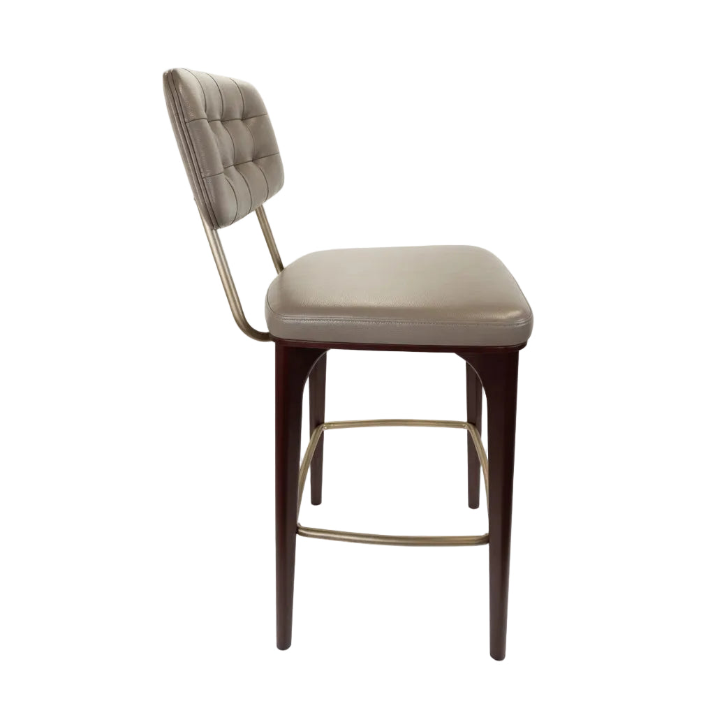 Upholstered bar stool with tufted back and beige seat, dark wood legs and gold footrest bar.