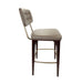 Upholstered bar stool with tufted back and beige seat, dark wood legs and gold footrest bar.