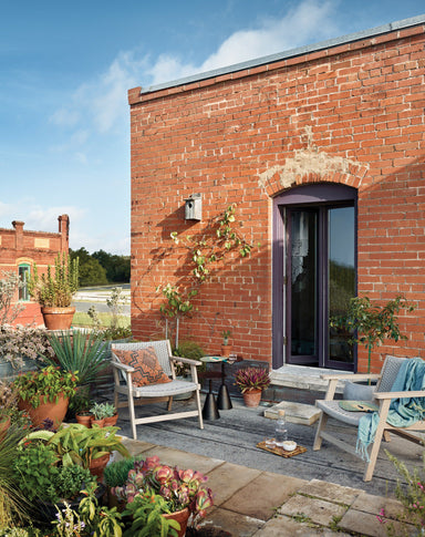 Outdoor scene Delano Outdoor Chair with a weathered grey teak frame and thick handwoven grey rope seating
