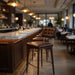Upholstered bar stool with tufted back and brown seat, gold base and square footrest.