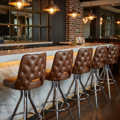 Row of brown leather Harley Porcini bar stools in a modern bar setting with marble counter and brick wall 