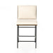 Counter stool with cream fabric seat and backrest, black metal frame, and footrest