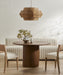 Dining room with a round wooden table, chairs, and a wicker pendant light.