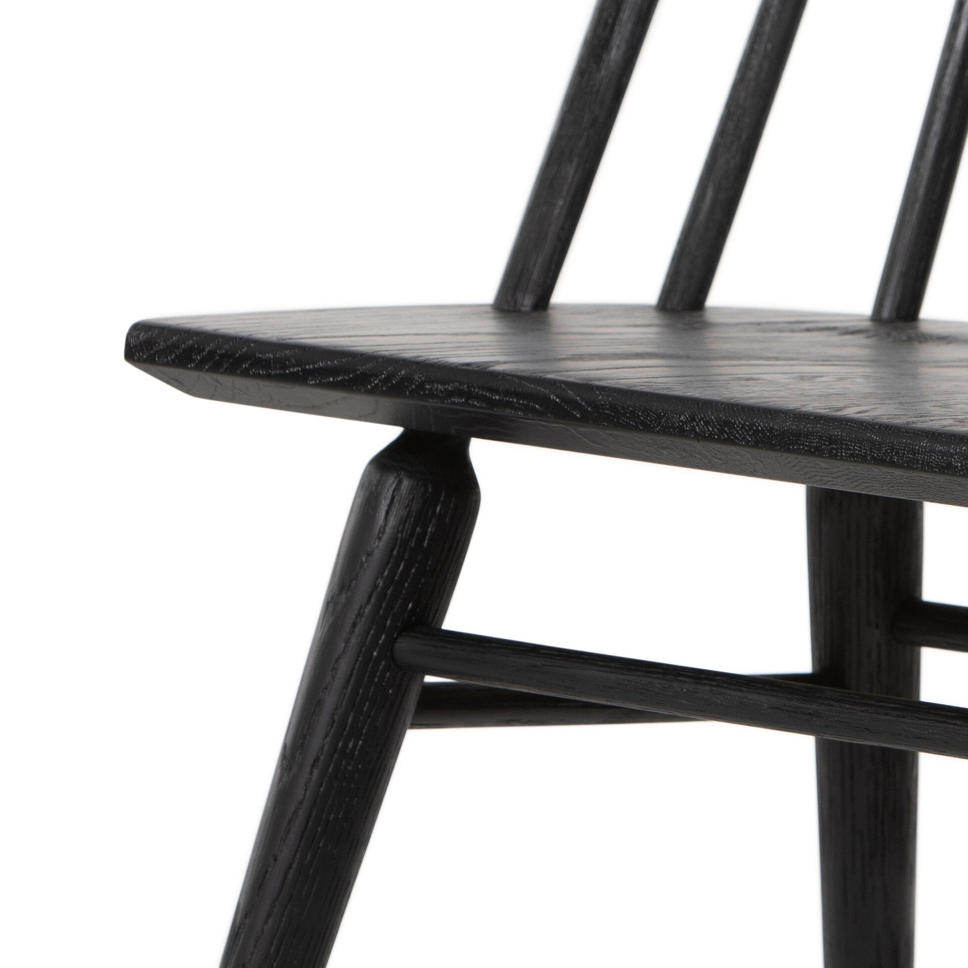 Close-up of dark wood chair arm-free seat edge and supporting stretcher, textured grain