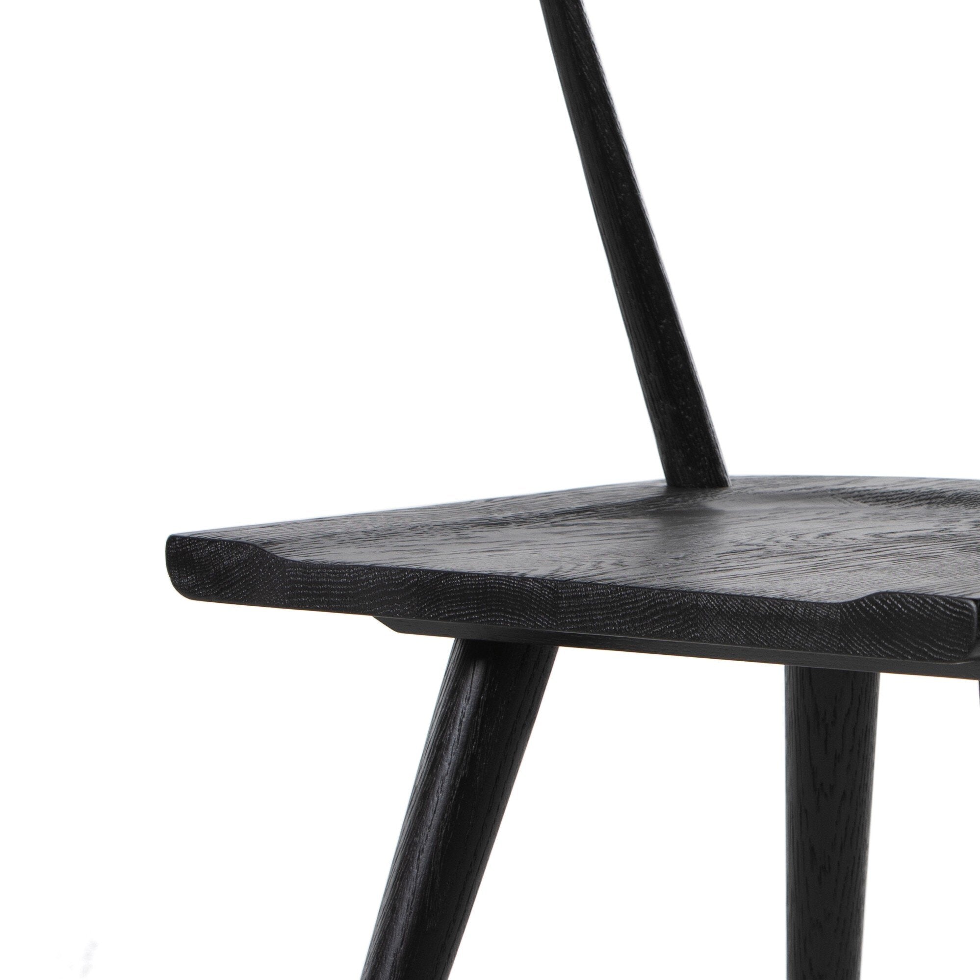 Black wooden chair on a white background. Seat Detail Ripley Dining Chair in Black Oak with mid-century Windsor-style sculptural silhouette.