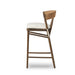 Brown wood bar stool with light upholstered seat, woven back, and side apron