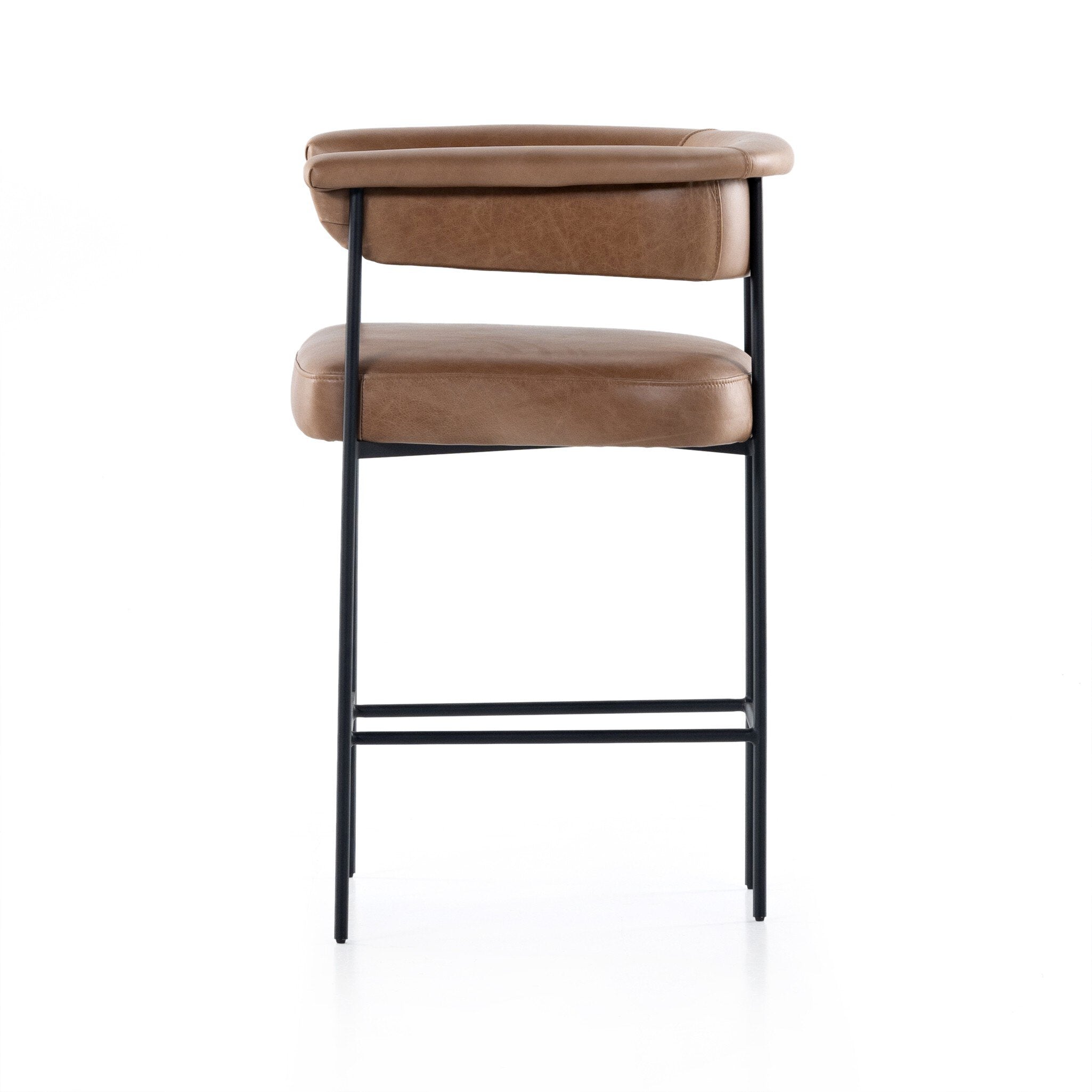 Tan counter stool with cushioned back and seat, rounded arms, and black metal legs