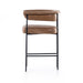 Tan counter stool with cushioned back and seat, rounded arms, and black metal legs