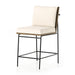 Counter stool with cream upholstered seat and tall backrest, black metal legs and footrest