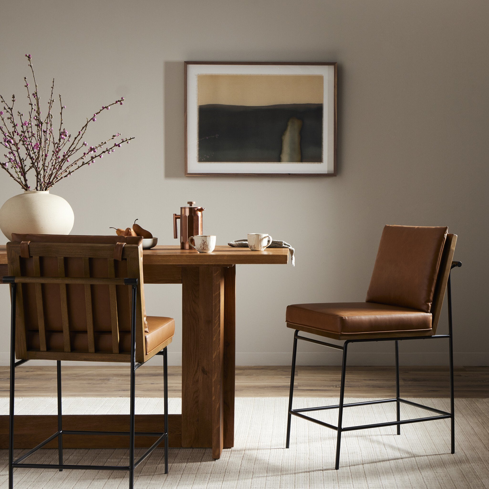 Counter stool with tan leather-look upholstery, tall back and black metal base with footrest