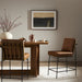 Counter stool with tan leather-look upholstery, tall back and black metal base with footrest