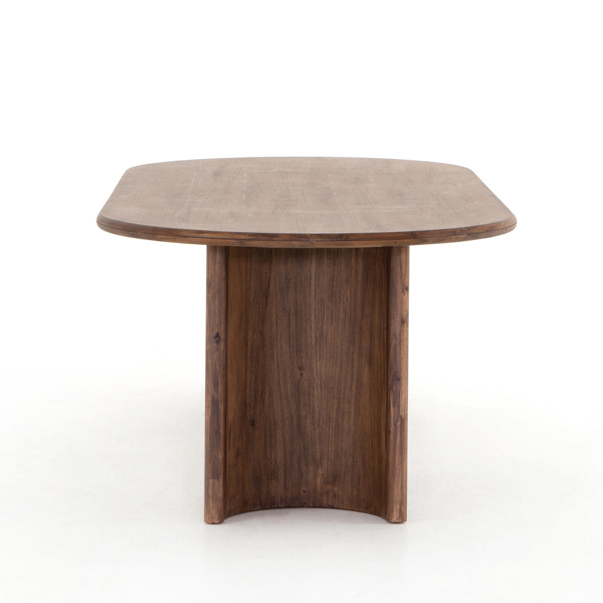 Side view Paden Dining Table in Seasoned Brown Acacia with crescent-shaped legs and an oval tabletop