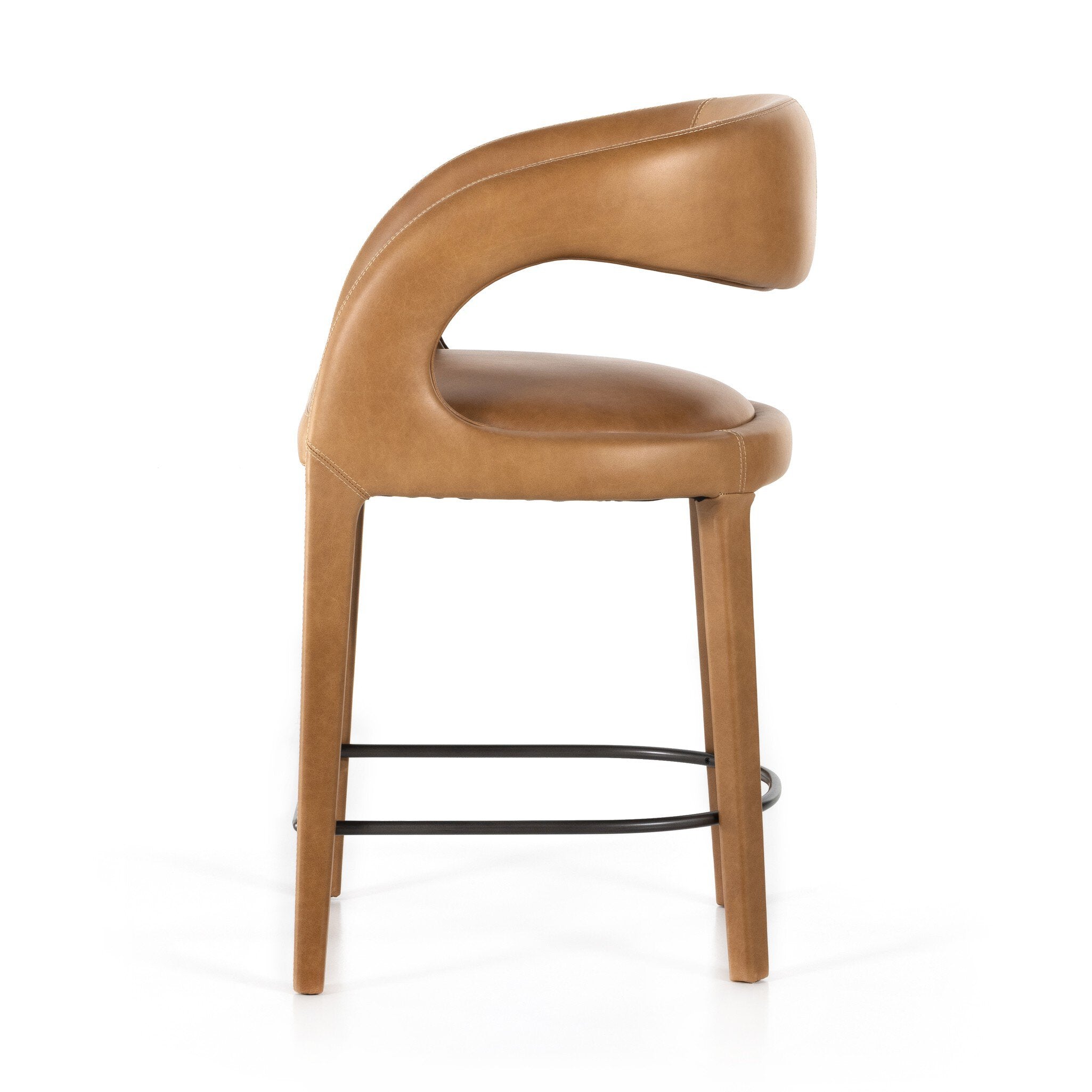 Counter stool side view with tan upholstered seat and curved armrest, wood legs, black footrest.
