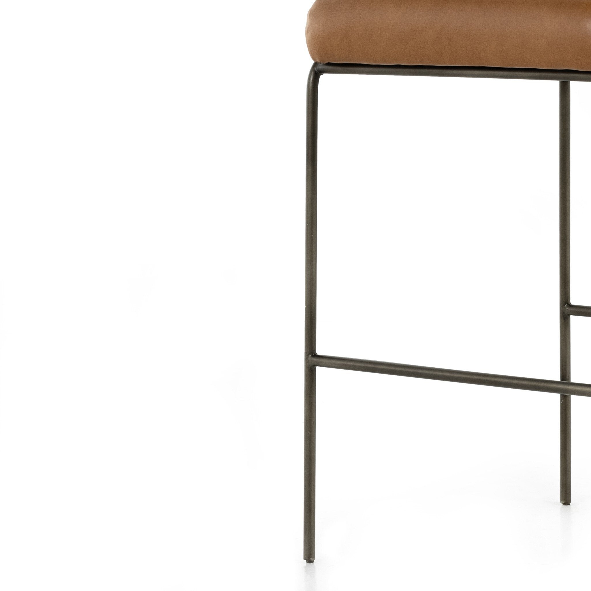 Brown upholstered bar stool seat edge with dark metal frame and crossbar