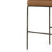 Brown upholstered bar stool seat edge with dark metal frame and crossbar