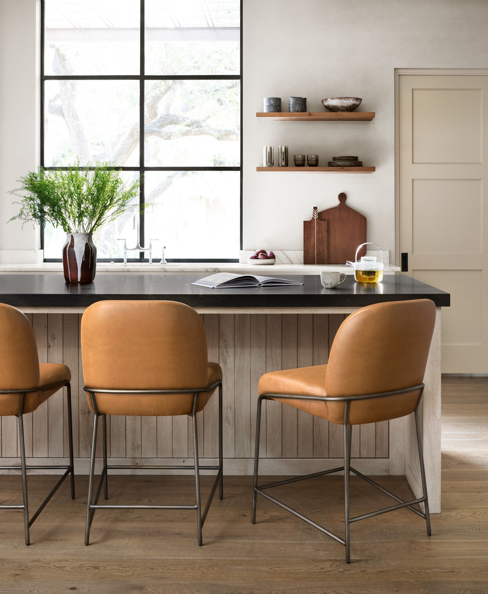 Pair of brown bar stools with padded seats, arched backs, and black metal frames.