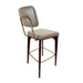 Upholstered bar stool with tufted back and beige seat, curved metal frame and dark wood legs.