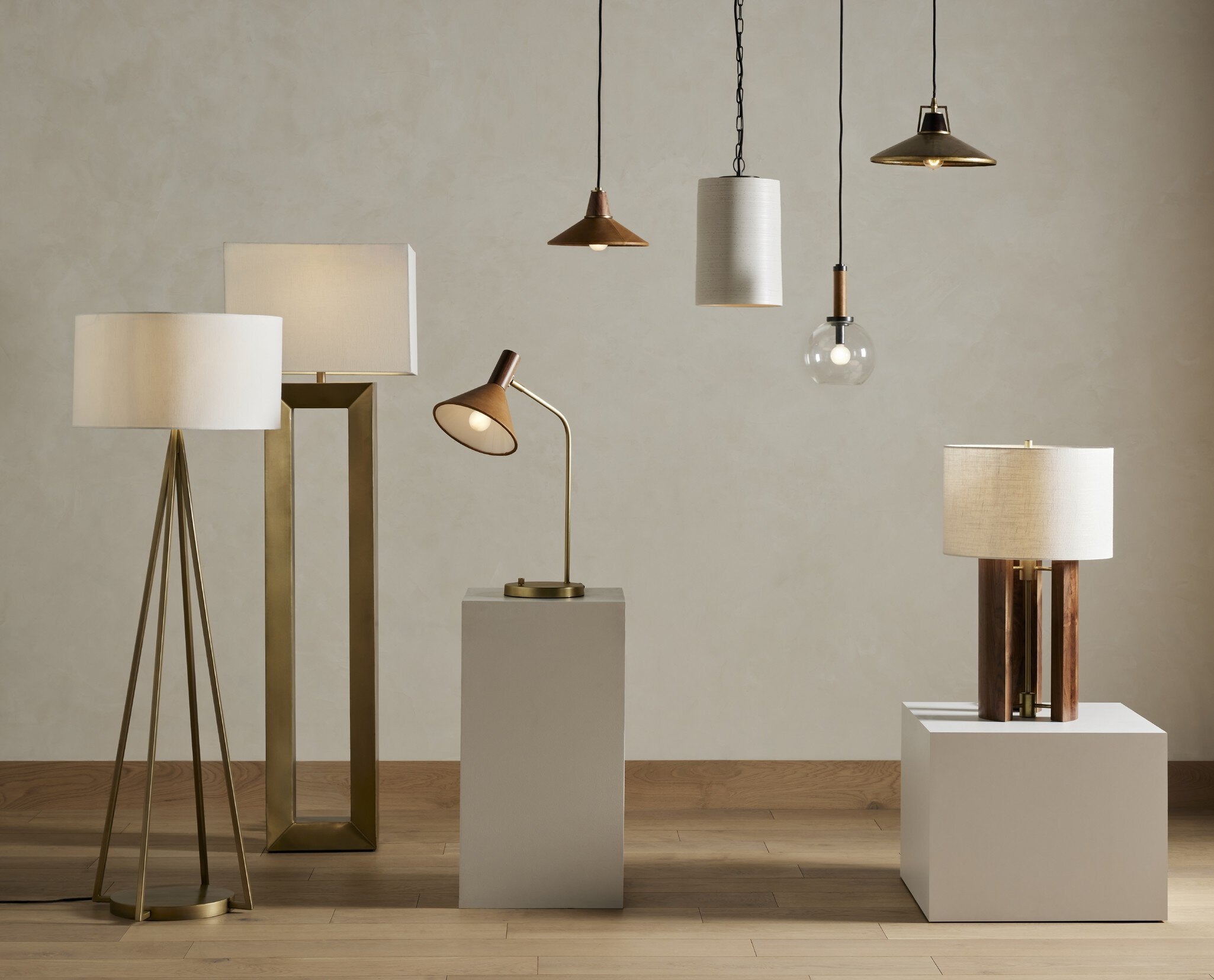 Various lamps including floor, table, and pendant lights on neutral background showing Cullen pendant light with a camel leather shade and natural walnut finial 