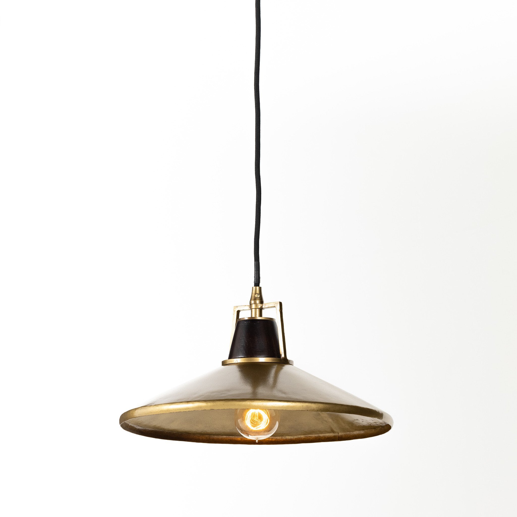 Warmly lit Novak 10-inch hand-hammered antique brass pendant light with perforated metal edge detail 