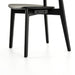 Black armless dining chair showing rounded seat, backrest, and four angled legs.