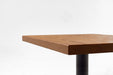 Red oak tabletop edge showing thickness with black pedestal leg