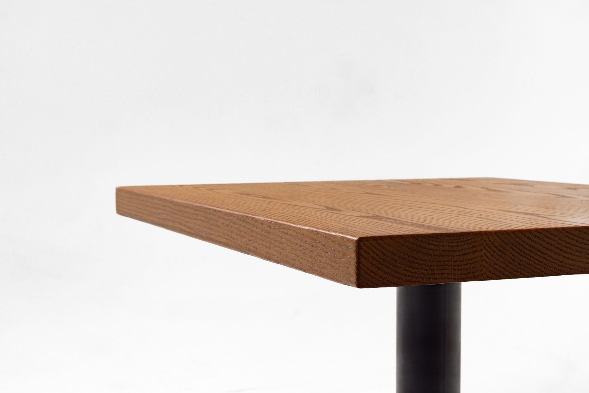 Red oak tabletop edge showing thickness with black pedestal leg