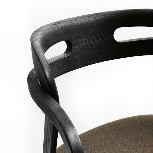 Close-up of dark wood arm chair back with circular cutouts and armrest