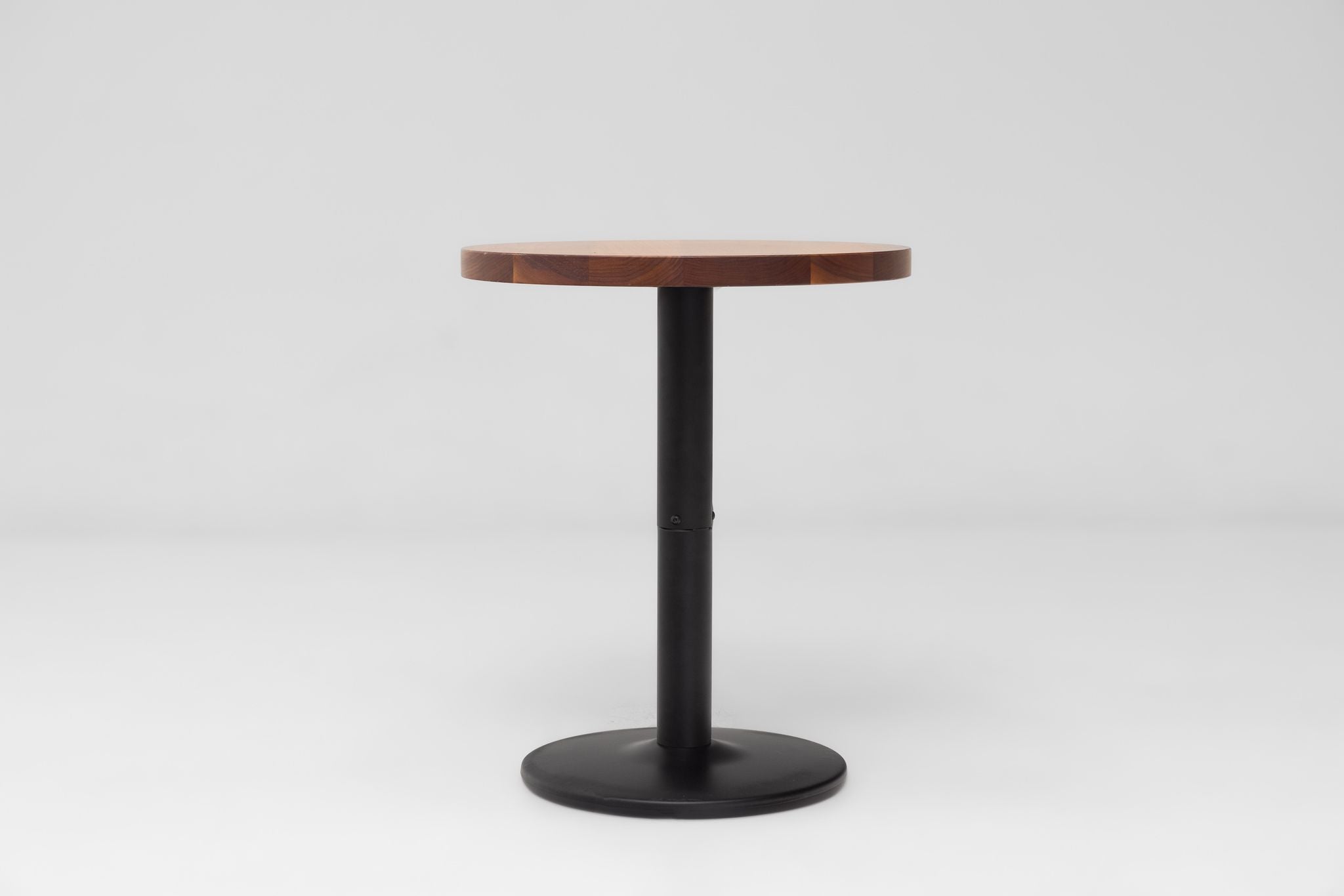 Round walnut table top with dark-brown finish mounted on a black pedestal base.