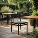 Dark outdoor side chair with slatted seat and back, viewed in patio setting