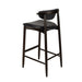 Bar stool with black upholstered seat and curved back, dark wood legs, footrest frame