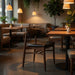 Dark brown side chair with black upholstered seat and rounded backrest in a dining setting