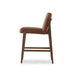 Brown upholstered counter stool with rounded seat and back, dark wood base, side view