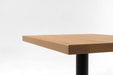 Ash table top corner with smooth edge and natural wood grain pattern, on black base