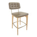 Upholstered bar stool with tufted back and beige seat, light wood legs and gold footrest.